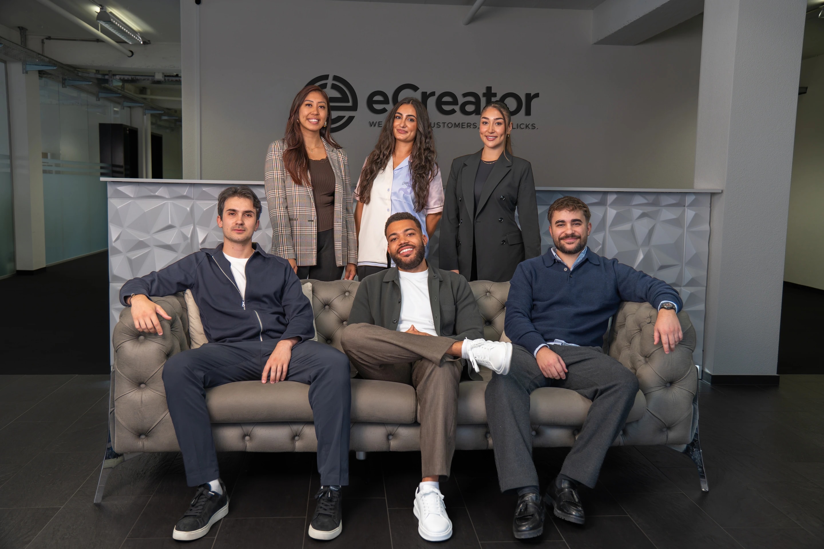 Das Team von eCreator beim Team-Shooting: drei Frauen stehen hinter dem Sofa, drei Männer sitzen davor
